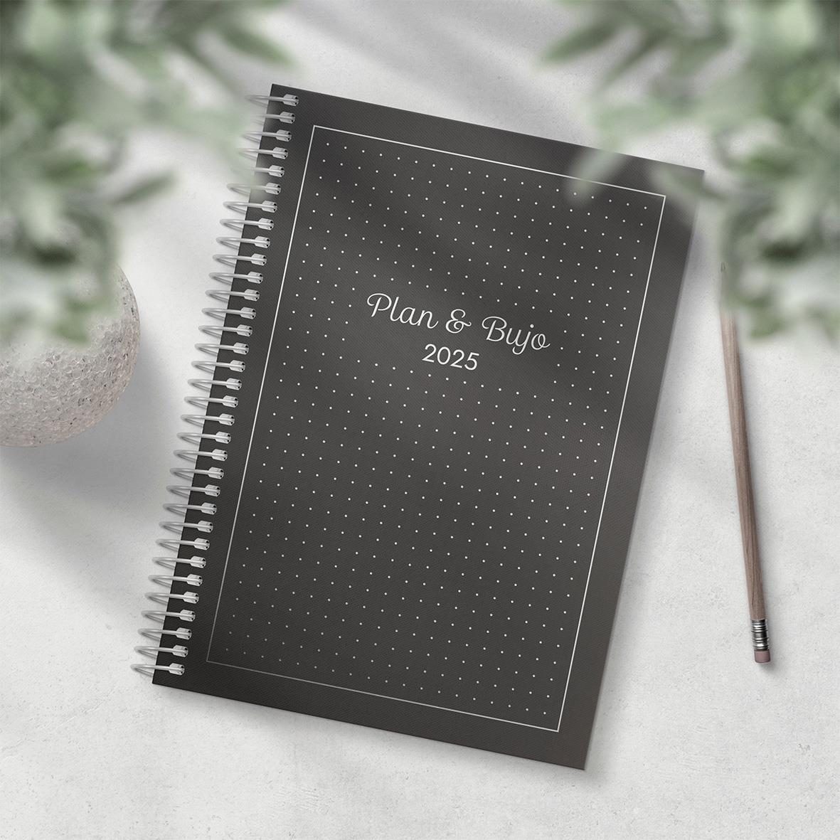Plan & BuJo 2025 A5 planerings- och bullet journal med svart omslag och spiralrygg på ett bord