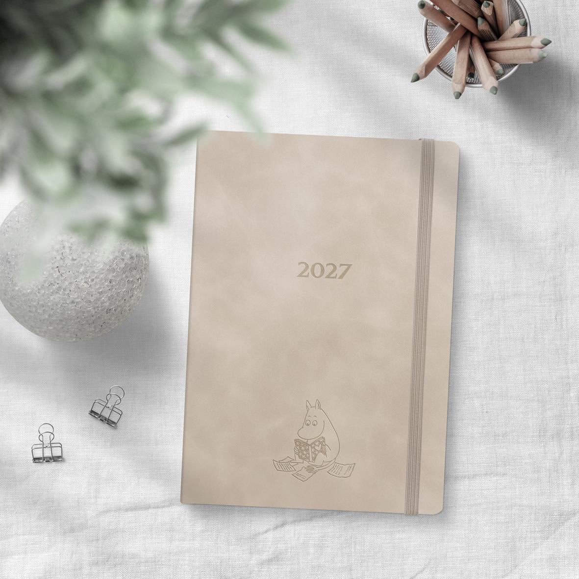 Öppningssida i almanacka för augusti 2026 med veckodagar och en liten tecknad figur i botten