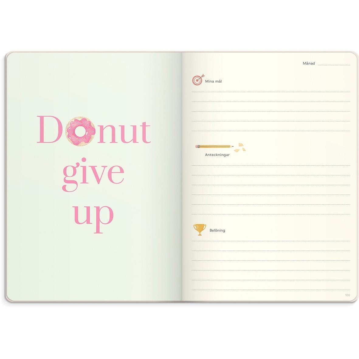 Öppen almanacka med rosa text Donut give up och linjerad sida för anteckningar i beige färg