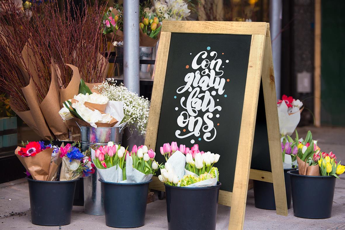 Gatuställ med blomsterarrangemang och svart tavla med vit text