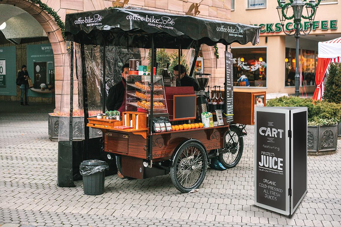 Mobil matvagn med påbyggnadsbar rostfri yta och skrivyta, utomhusmiljö med café och butiker i bakgrunden