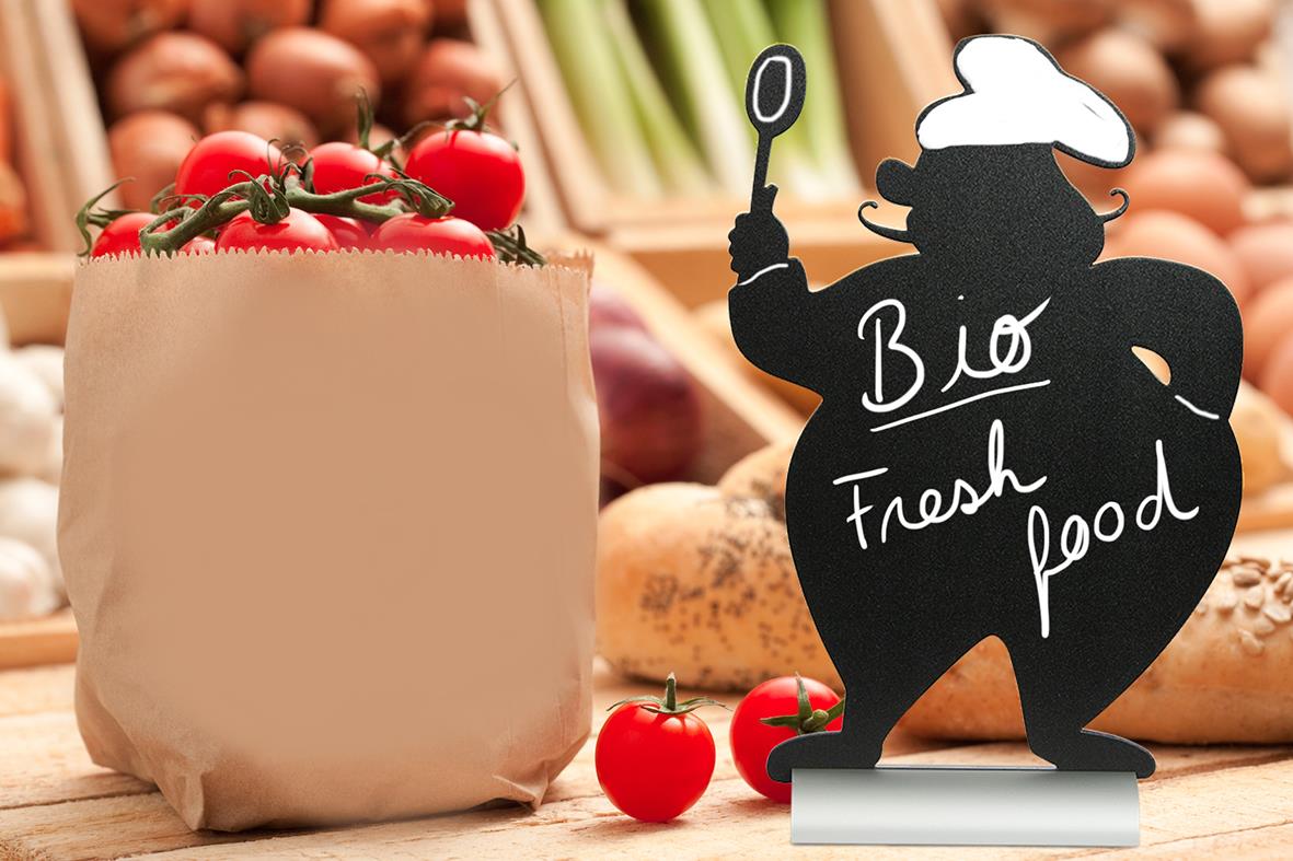 Siluett av kock med skylt för bio, färsk mat, tomater och grönsaker i bakgrunden