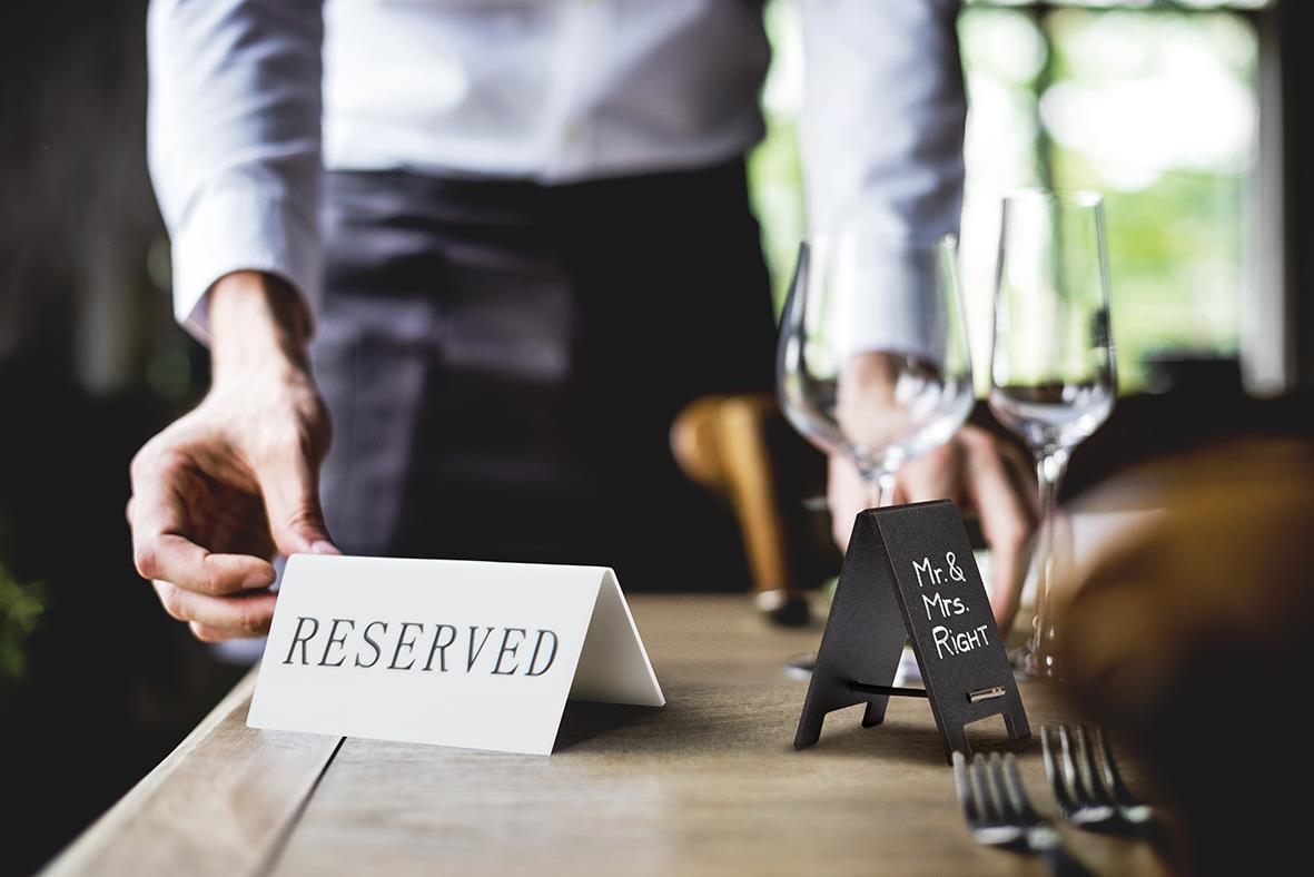 Bordsskylt Reserved och ett annat med MRS och MR, placerade på ett bord i ett restaurangmiljö
