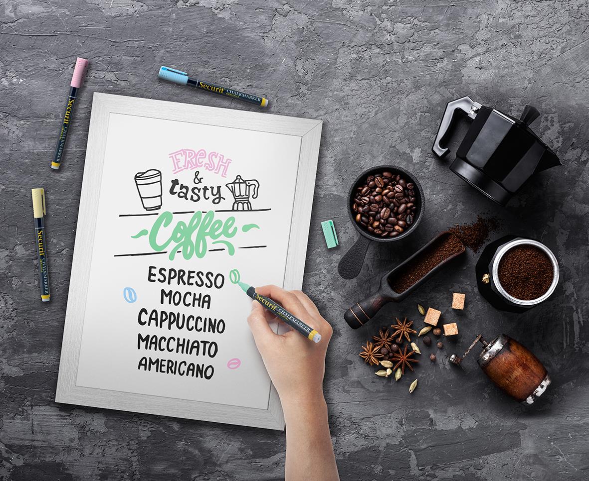 Vit griffeltavla för vägg med skrivyta för märkpennor, omgiven av kaffe- och kryddkapslar samt skrivredskap