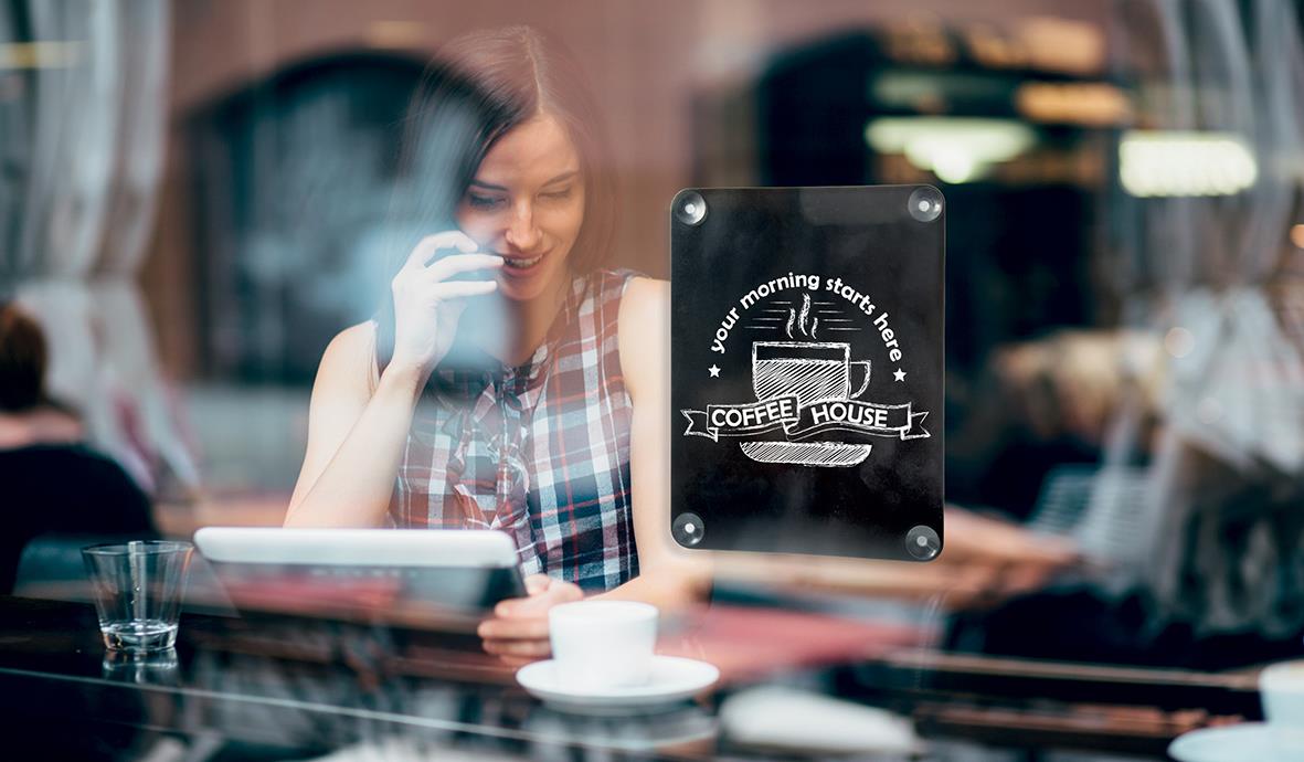 Kvinna som använder en svart dubbelsidig griffel med texten Coffee House på ett café