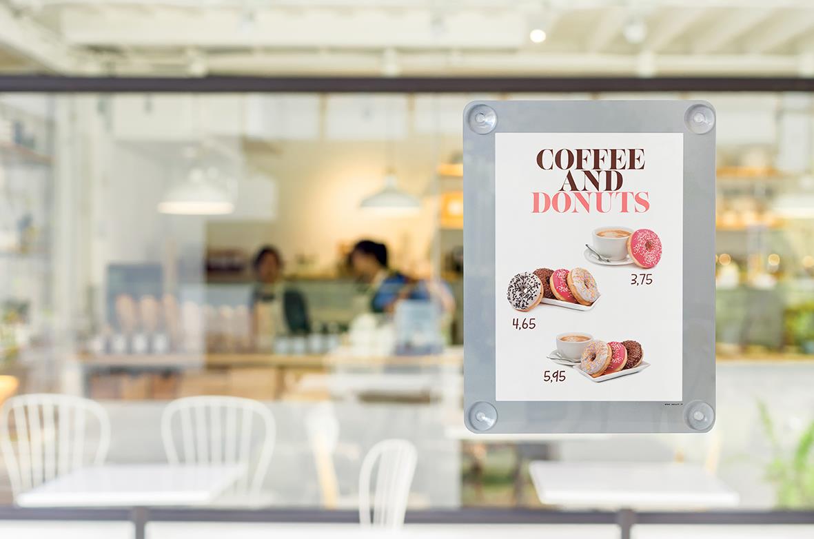 Skylt för kaffe och donuts med priser, placerad på fönster i ett café eller butik