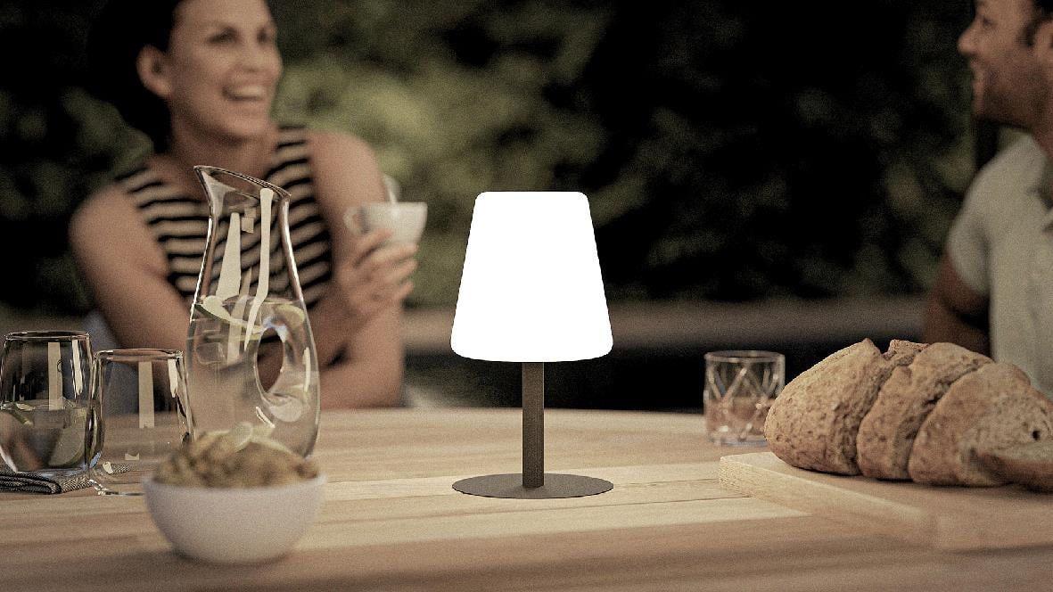 Bordslampa Securit med griffeltavla på ett bord med bröd och drycker, personer i bakgrunden