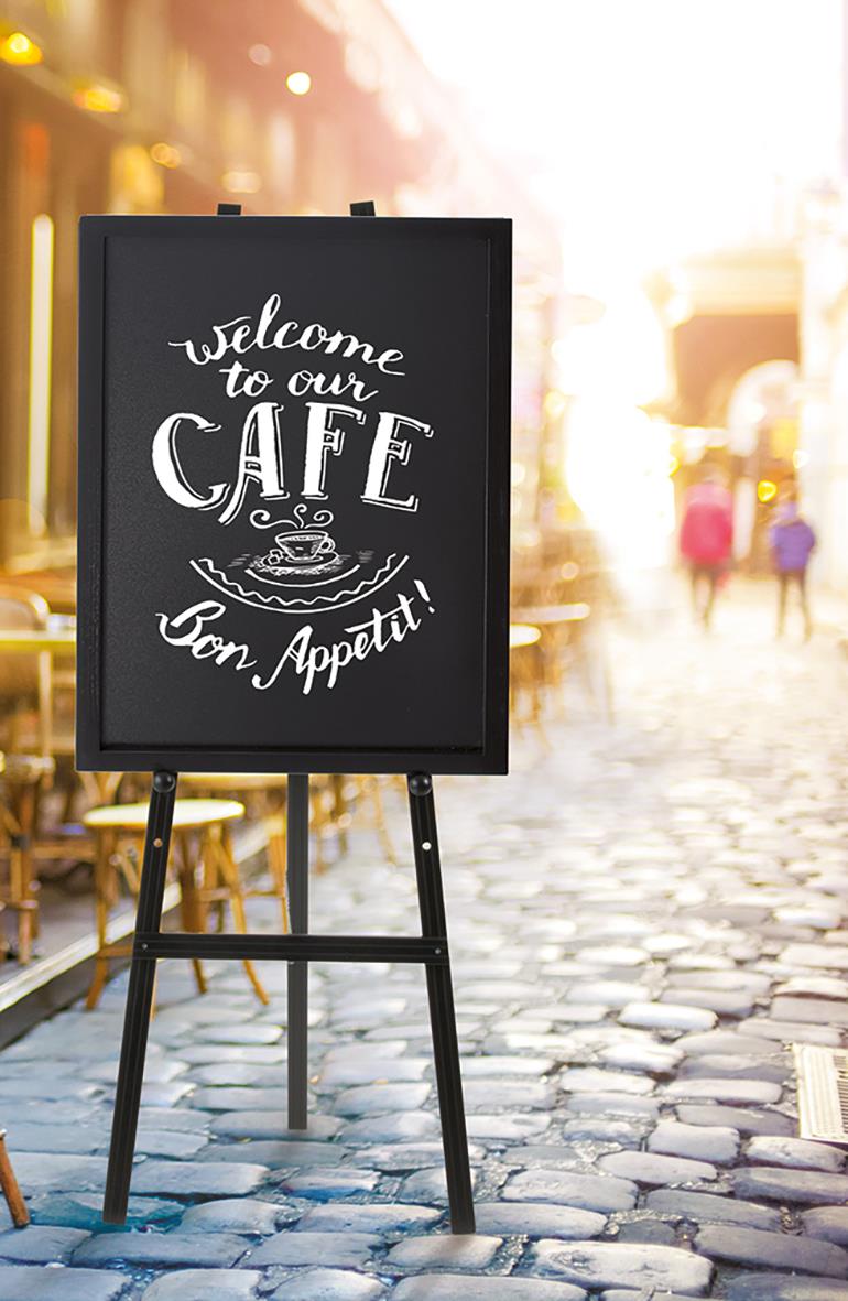 Golvstaffli med svart griffeltavla med text och illustration, utomhus på kullerstensgata, solnedgång