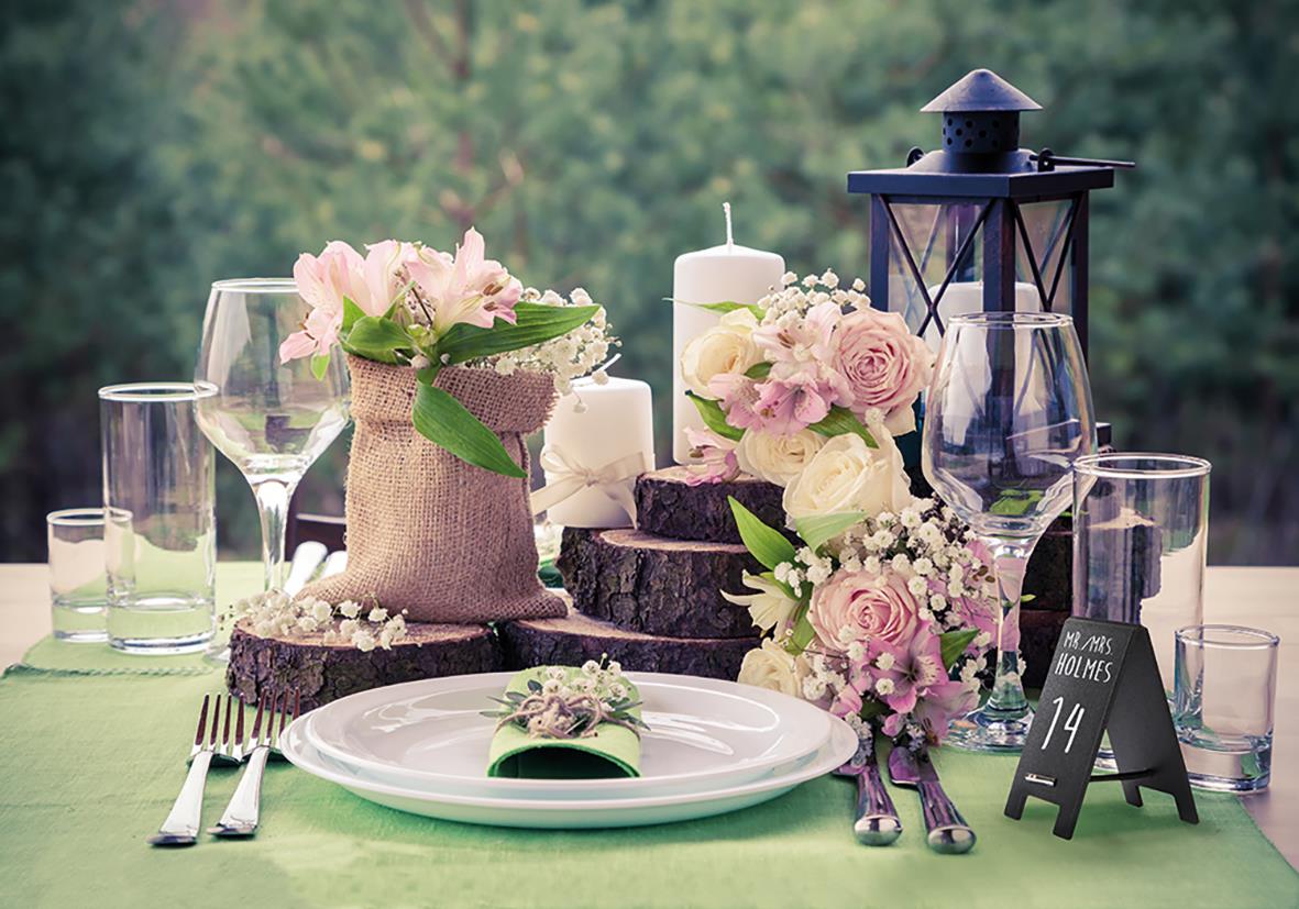 Dekorerad bordduk med blommor, ljus, glas, tallrik och griffeltavla för bord