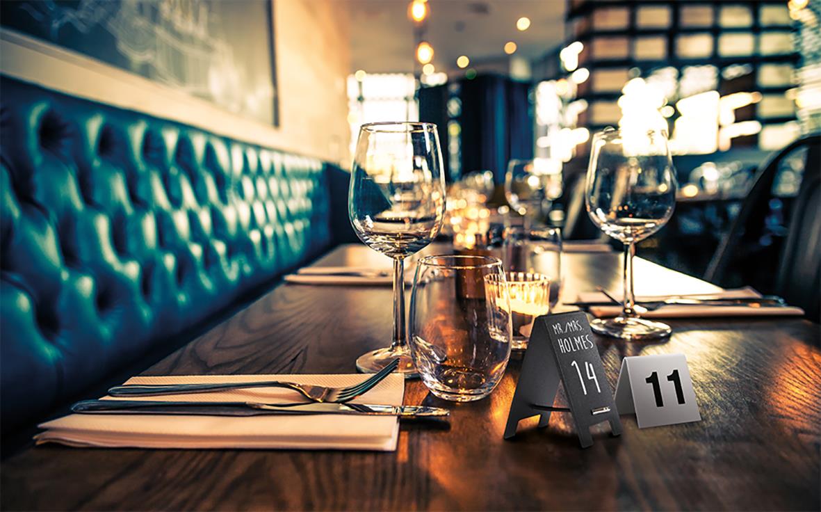 Bord med glas, bestick och griffeltavla i restaurangmiljö