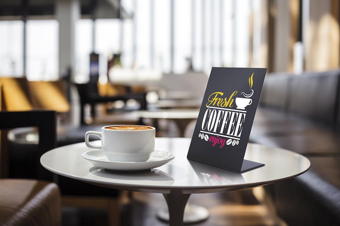 Svart griffeltavla i akryl med texten Fresh Coffee på ett bord i ett kafé