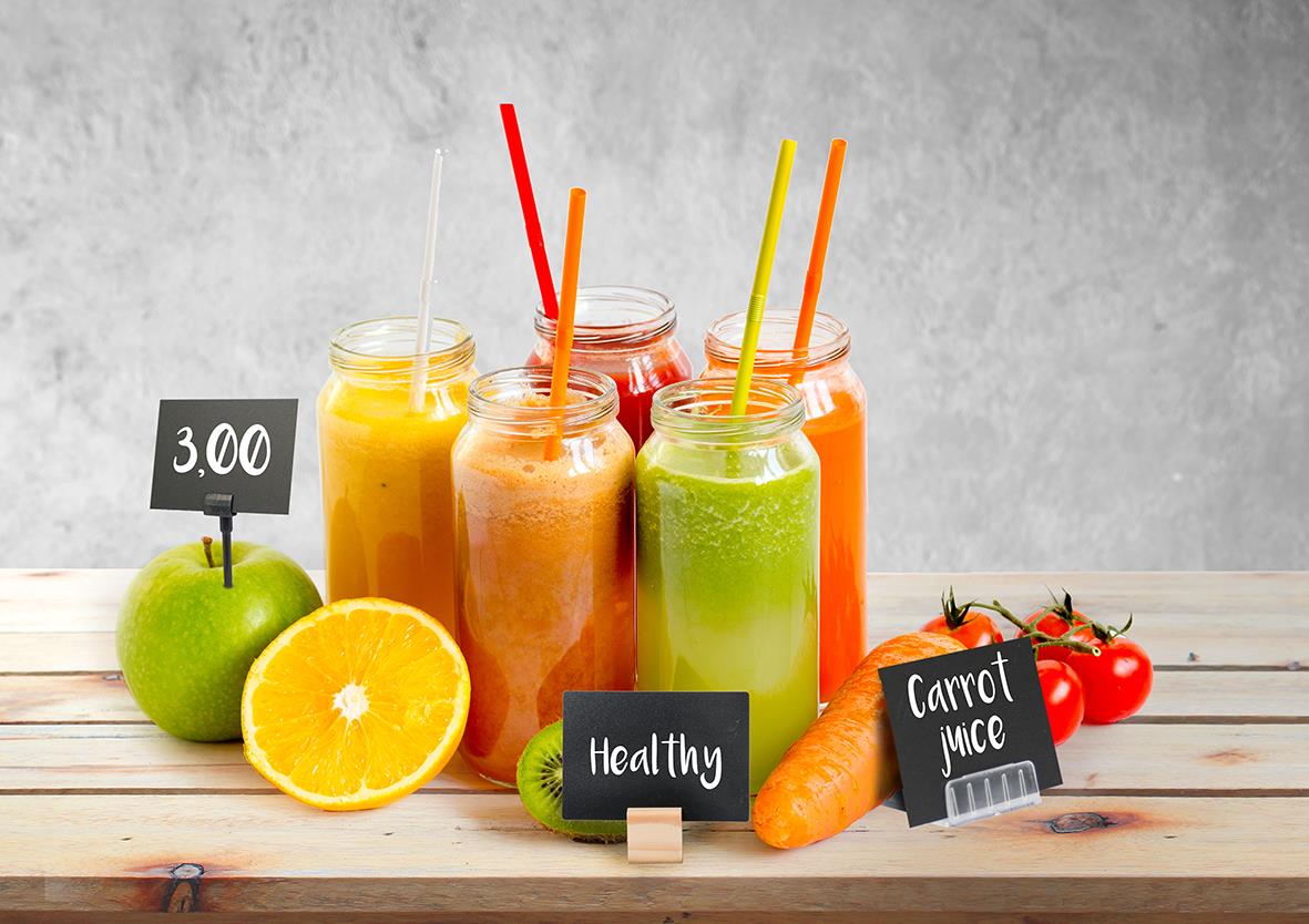 Färgglada smoothies i glas med sugrör, frukt och små skyltar med hälsobudskap på träbord