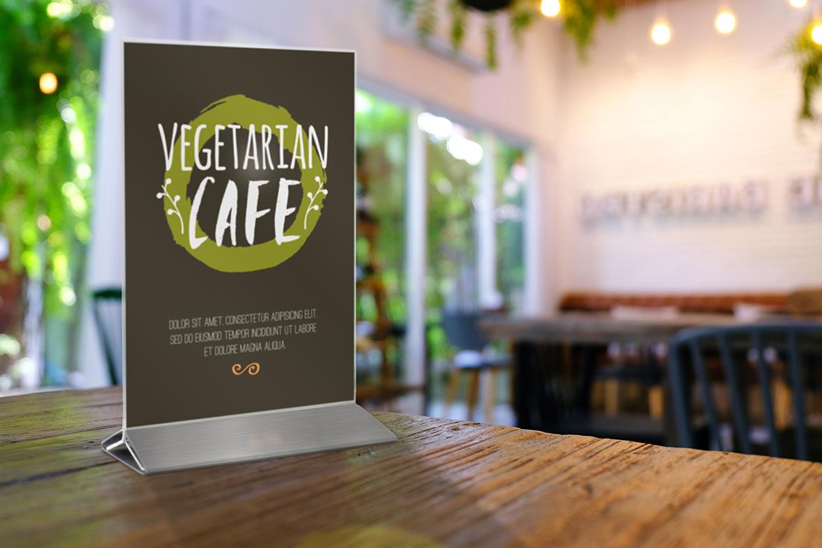 Vegetarian Café skylt med information om mat och dryck i ett café med stora fönster och inomhusbelysning
