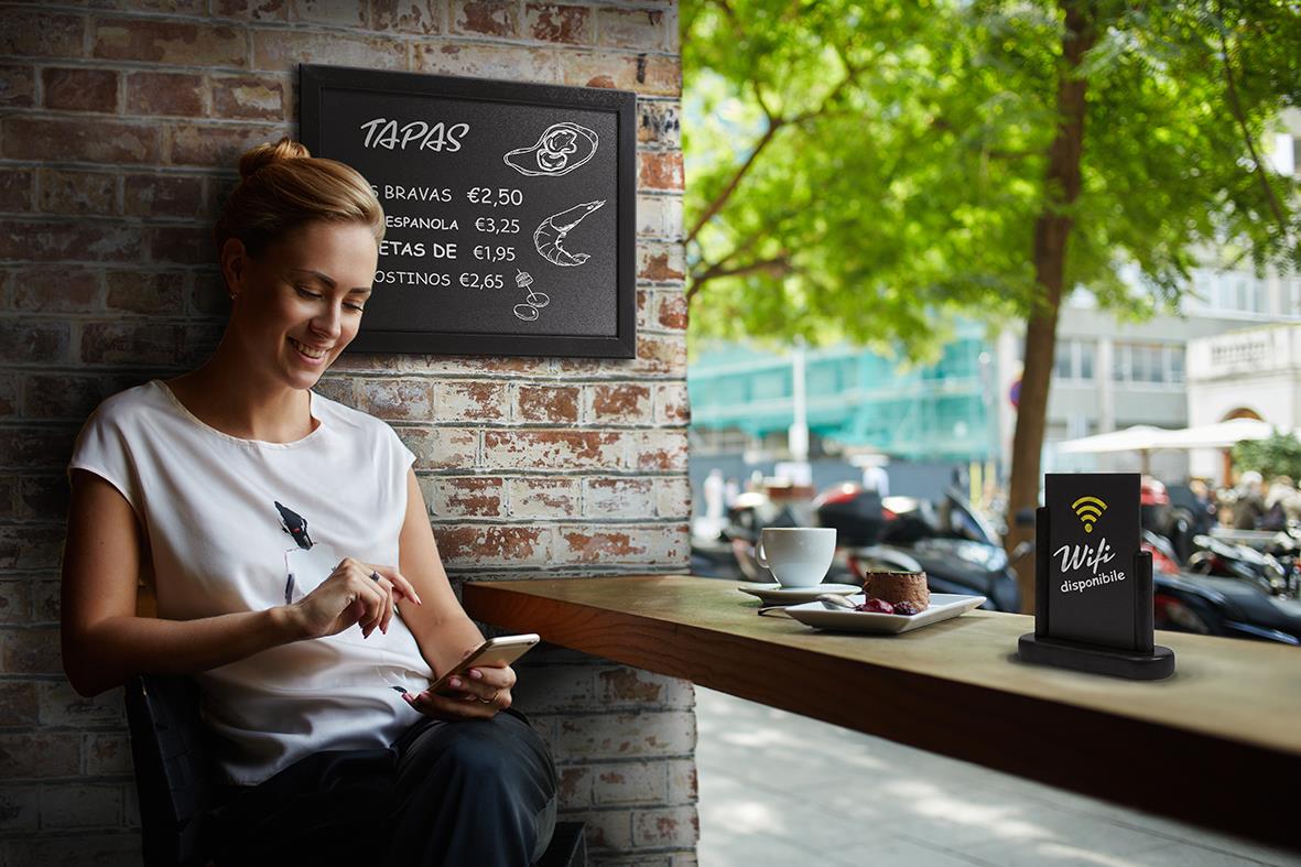 Kvinna skriver på svart griffeltavla utomhus med wifi-skylt i bakgrunden