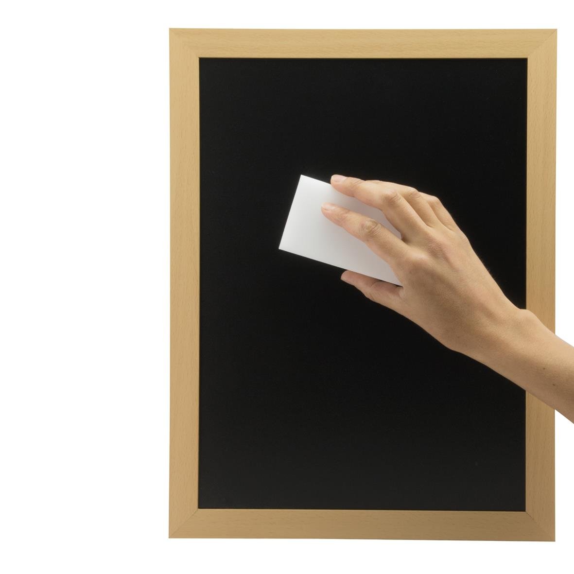 Hand som torkar en svart tavla med en vit trasa