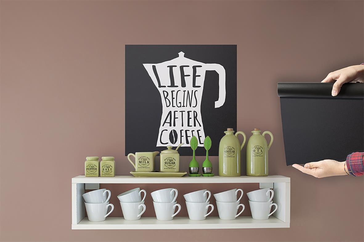 Svart griffeltavla med text Life begins after coffee och en hand som sätter på den