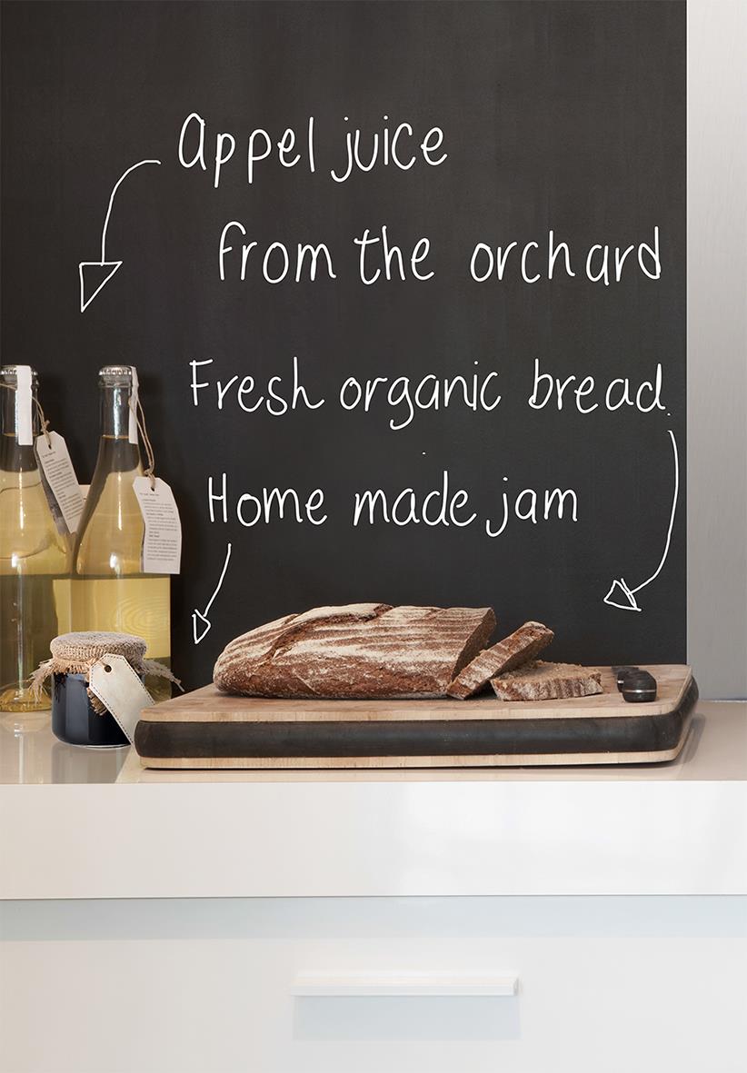 Svart griffeltavla med handskrivna anteckningar om äppeljuice, färskt bröd och hemmagjord sylt, samt en brödlimpa på skärbräda