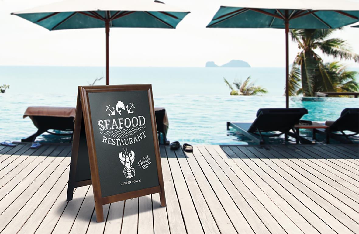 Uteservering med parasoller, strand, och en skylt för seafood restaurant