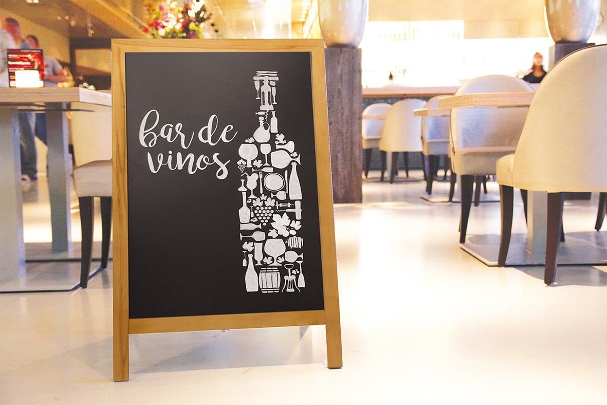 Gatuställ med svart griffeltavla och teaksida, text bar de vinos, i ett café eller restaurangmiljö