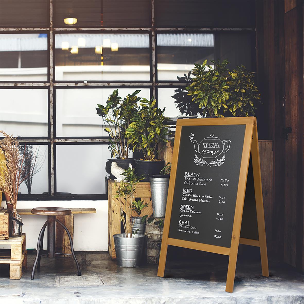 Gatuställ Securit Woody Furu Teak 58x87cm med skrivyta framför ett fönster och växter