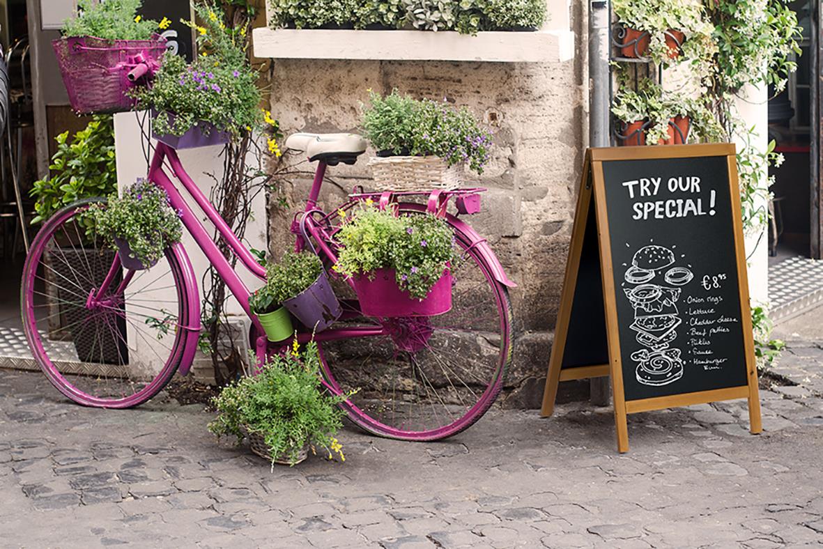 Gatuställ med rosa cykel och svart anslagstavla med text och illustrationer