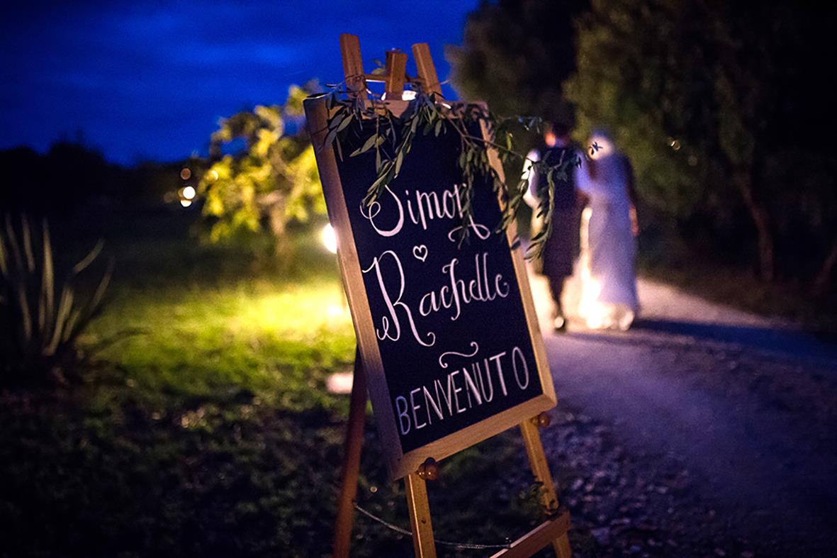 Golvstaffli Securit för griffeltavla i teak med välkomstmeddelande, utomhus vid kvällstid