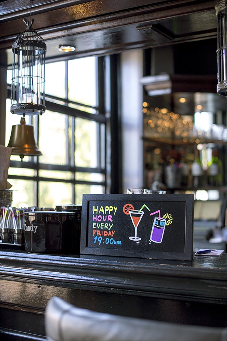 Svart griffeltavla för vägg med skrivyta, visar en neonfärgad meny för happy hour på en bar