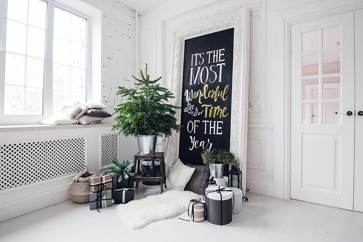 Vardagsrum med växter, kuddar och en svart tavla med text i ett ljust rum