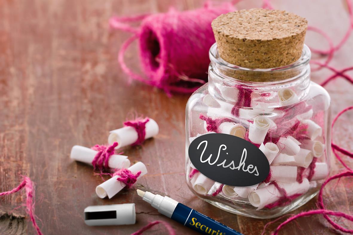 Svart oval griffelklistermärke med skrivyta och kork, fyllt med små vita och rosa klistermärken samt en penna