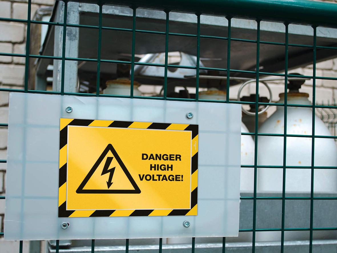 Varningsskylt med text DANGER HIGH VOLTAGE på gul och svart bakgrund, fäst på metallgaller