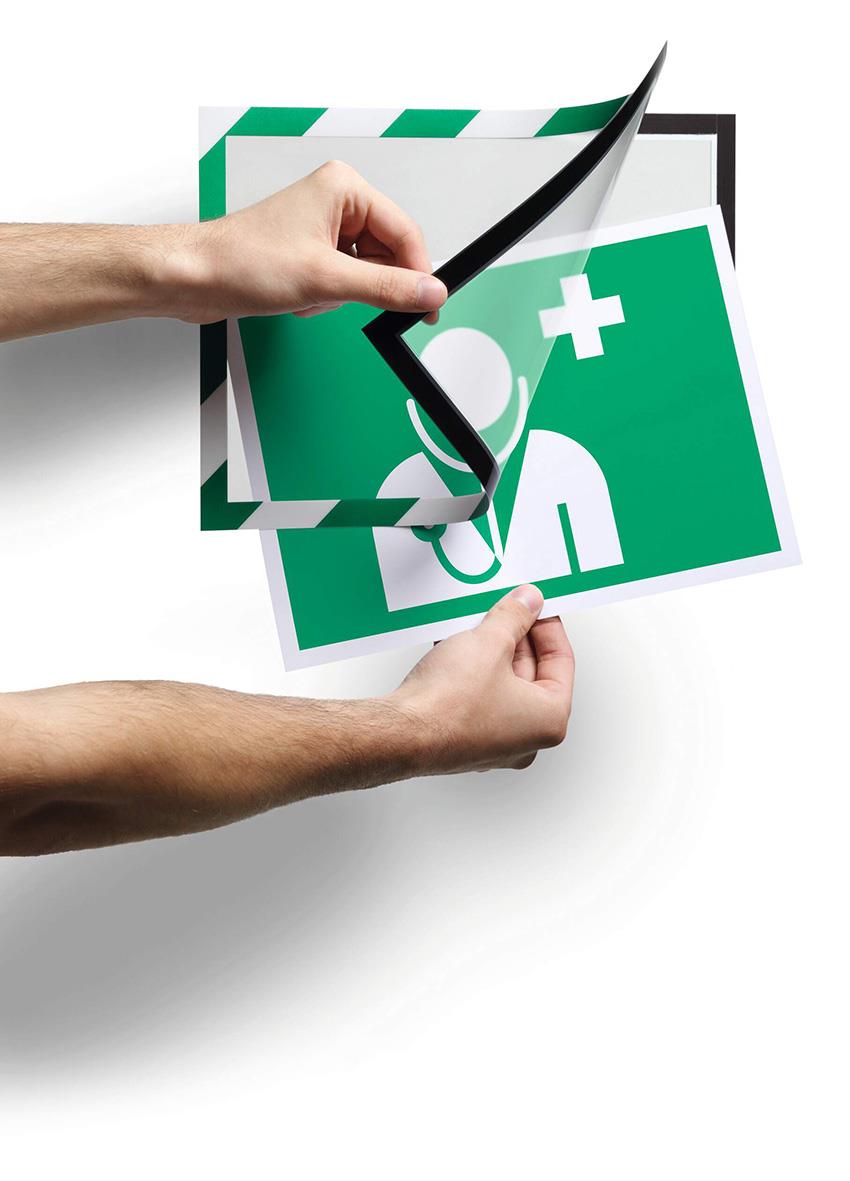 Självhäftande säkerhetsram i grönt/vitt för A4, visar en person som applicerar en skyddsskylt med medicinskt symbol.