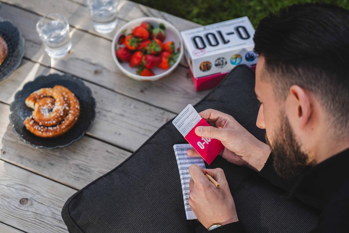 Man spelar ett spel med siffror 0-100 utomhus, med snacks och drycker på ett bord