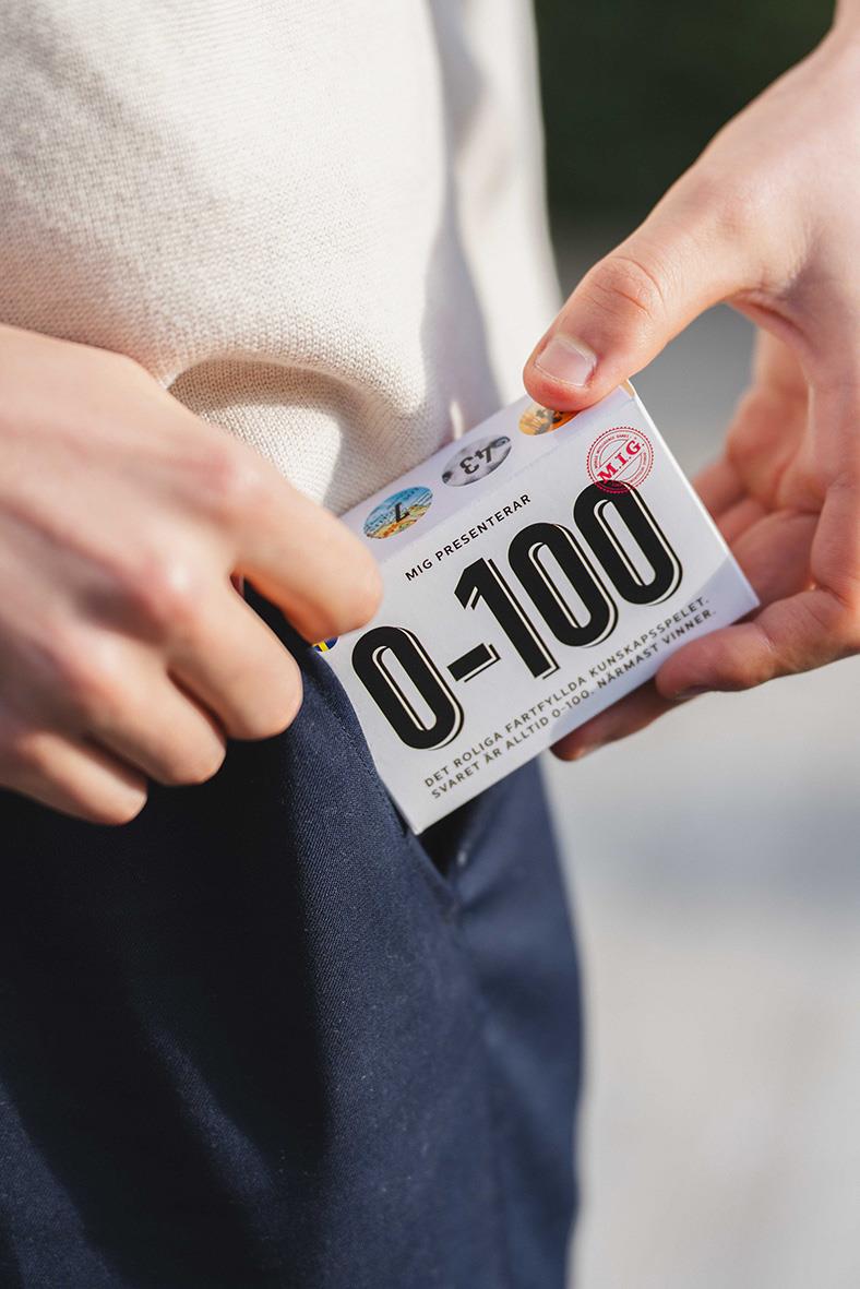 Person håller i ett kortspel MIG Mini 0-100, som visar siffrorna 0 till 100