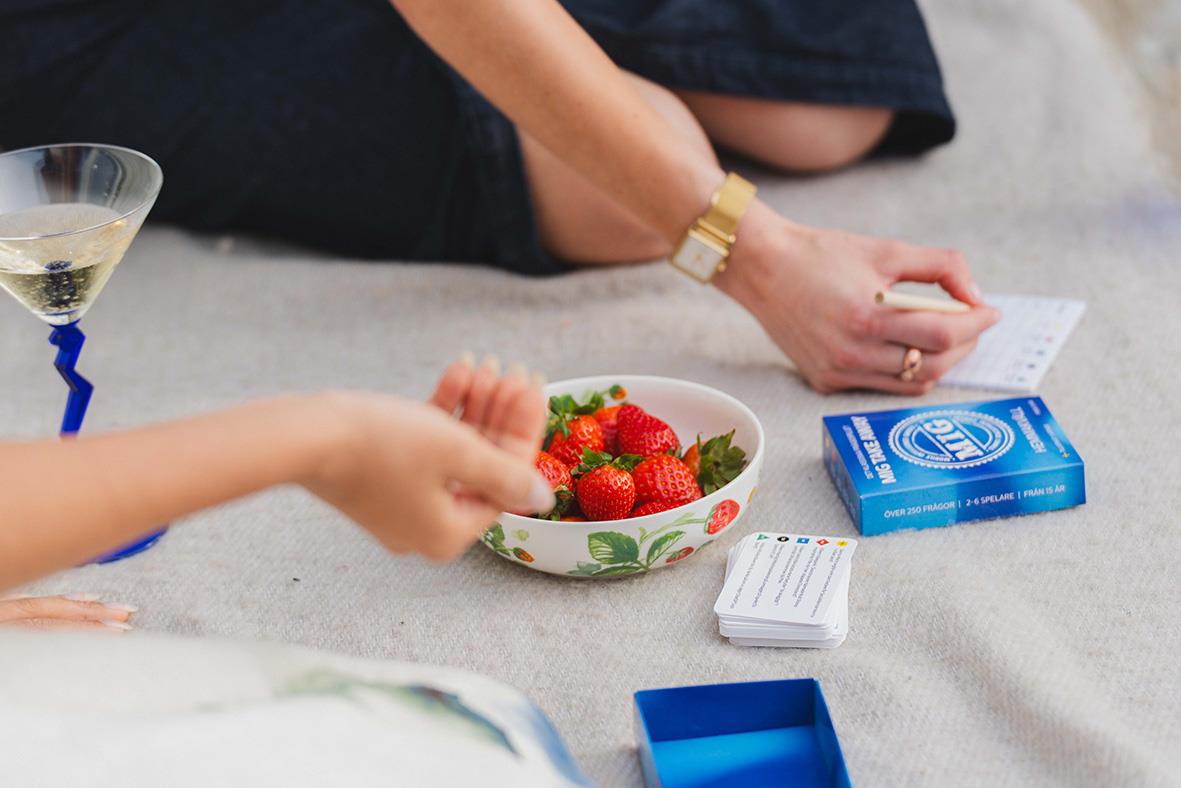 Person som spelar ett spel med jordgubbar, ett kort och en blå box på en matta