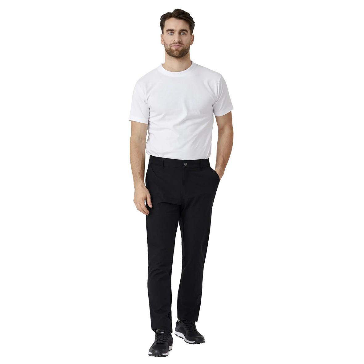 Man i vit T-shirt och svarta byxor står mot vit bakgrund