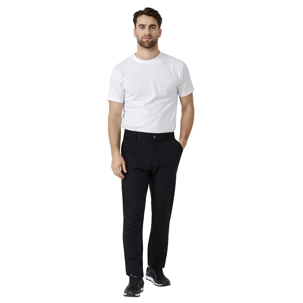 Man i vit t-shirt och svarta byxor står mot vit bakgrund