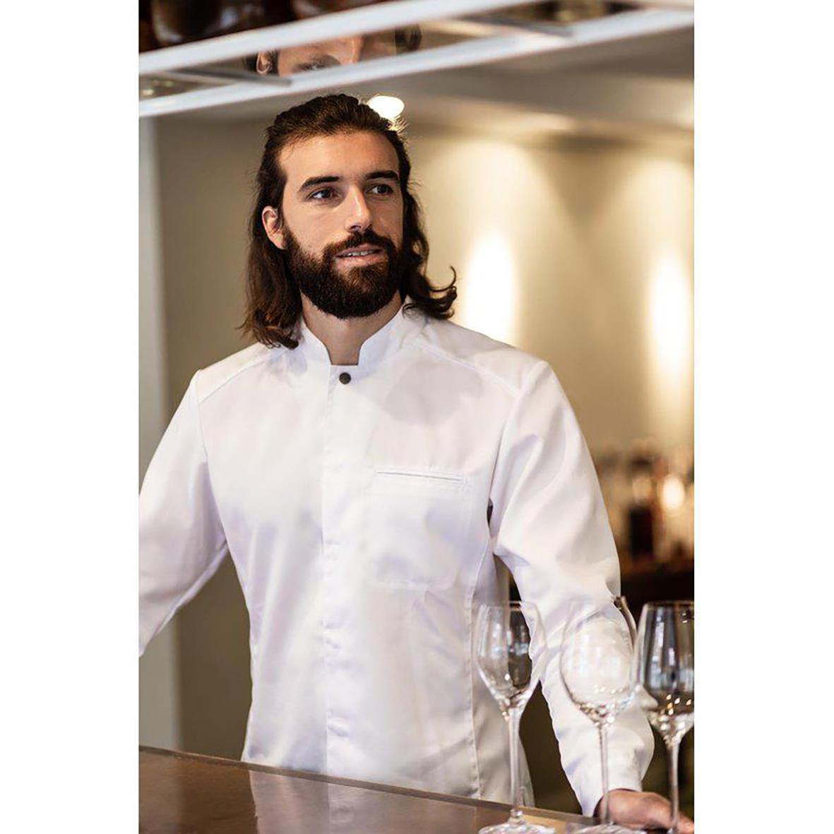 Man i vit kockskjorta med knappar, står bakom bar eller kök, med glas på bordet