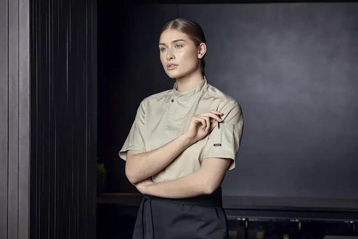 Kock i beige servicejacka Kentaur 23516 Sand 2XS står mot en mörk bakgrund