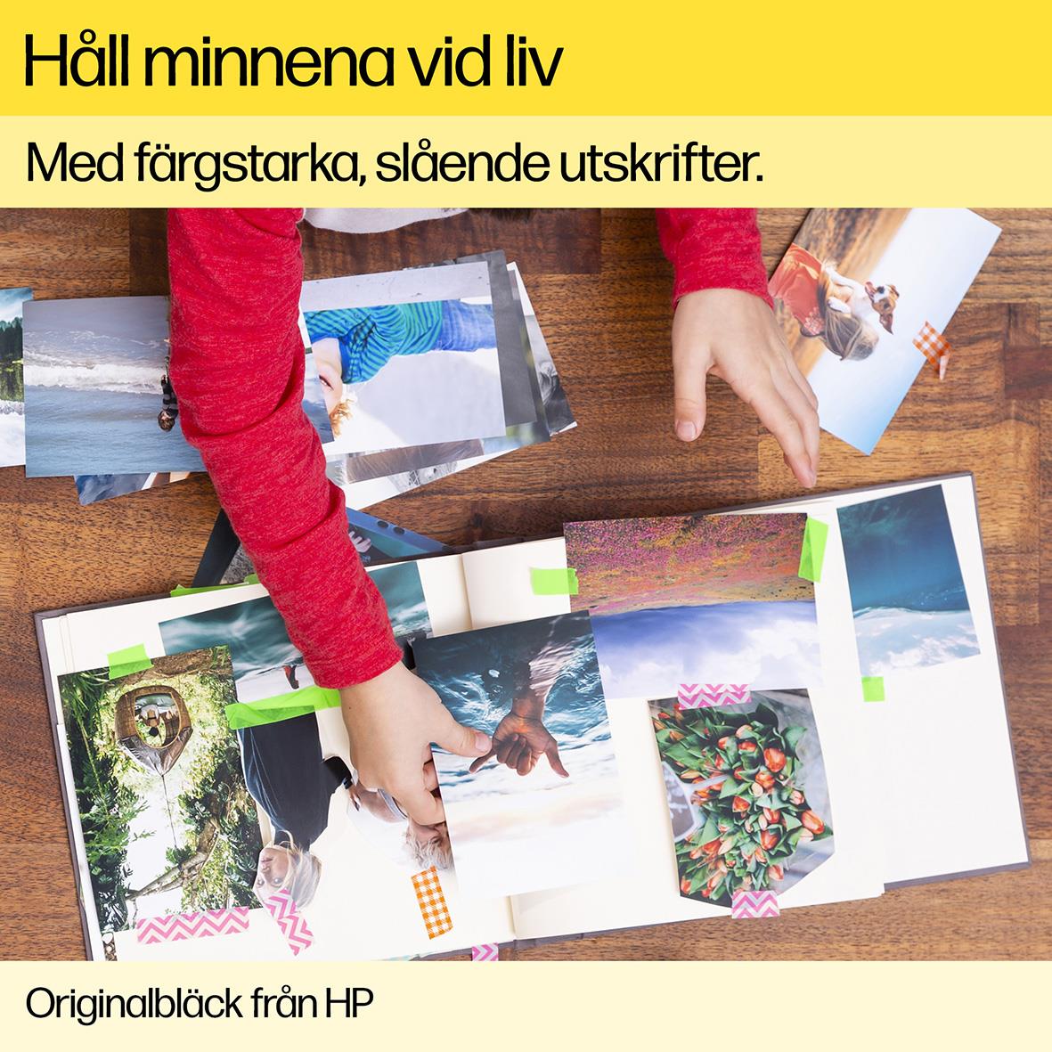 Person som visar ett fotoalbum med färgstarka bilder på ett träbord, hand som vänder blad