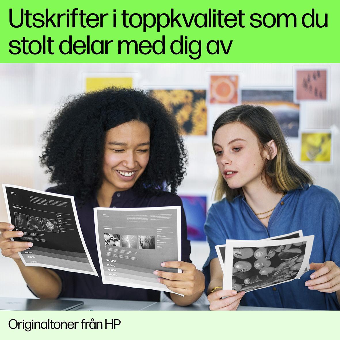 Två kvinnor tittar på utskrifter och bilder, en ler och ser nöjd ut, i ett kreativt arbetsrum med färgglada affischer på väggen