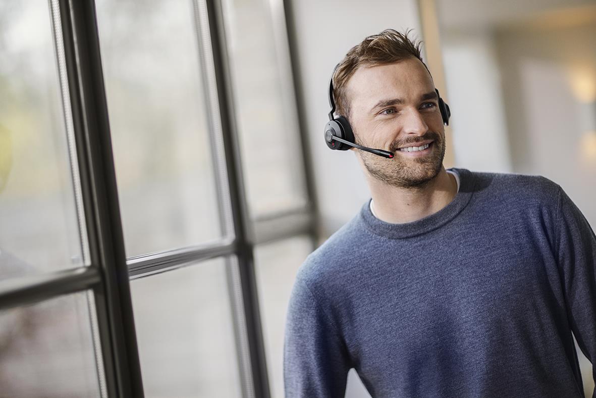 Man med headset Jabra Engage 45 SE Stereo som arbetar vid ett fönster