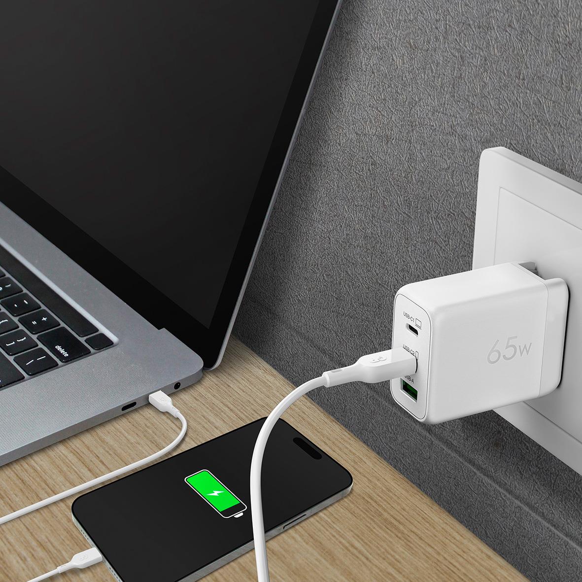 Väggladdare GP GaN PD 65W med 2 USB C och 1 USB A ansluten till vägguttag, laddar en smartphone