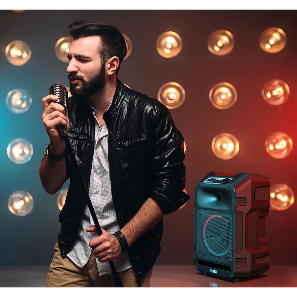 Man med mikrofon framför en högtalare med ljus i bakgrunden