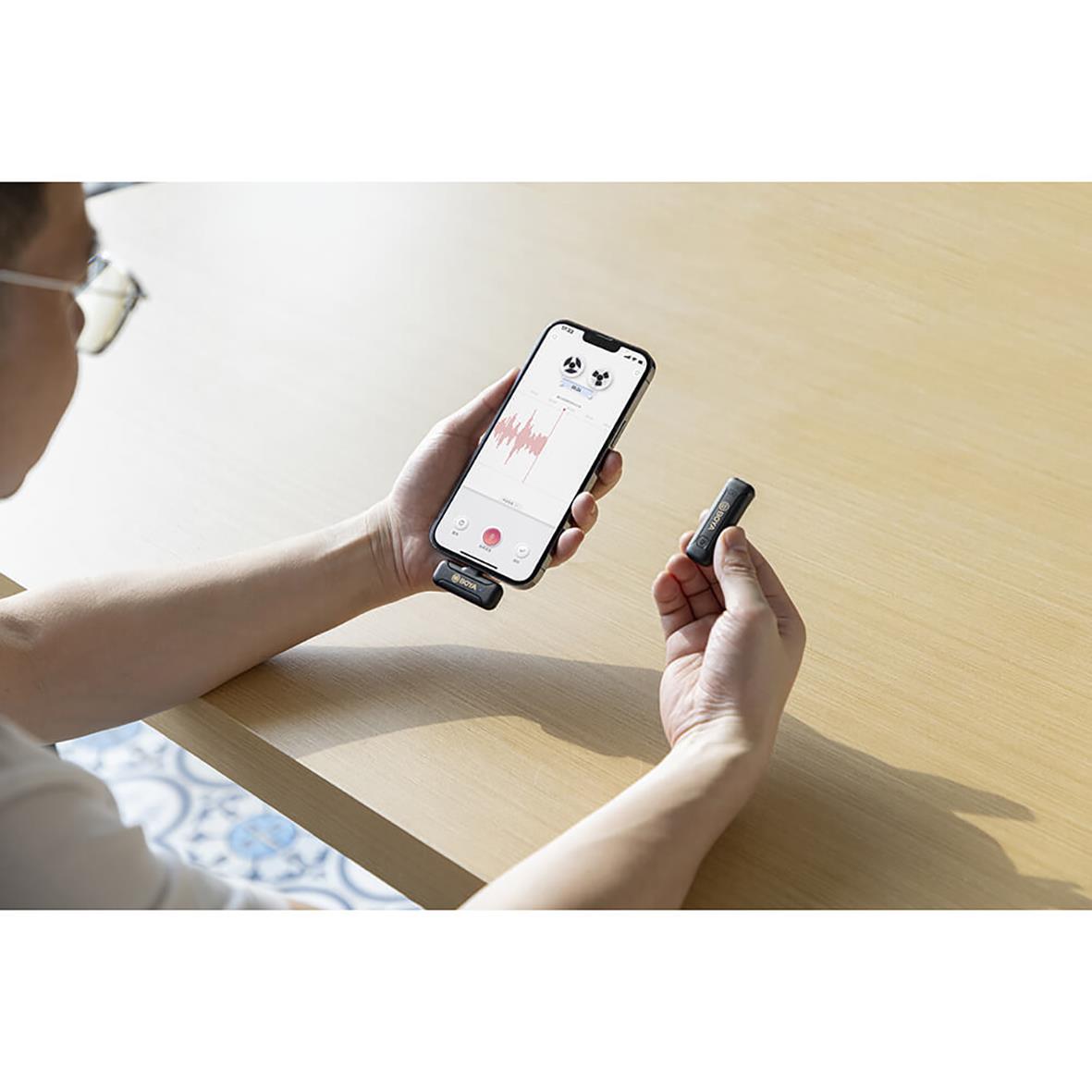 Person håller i ett trådlöst mikrofonmottagare och använder en smartphone för ljudinspelning