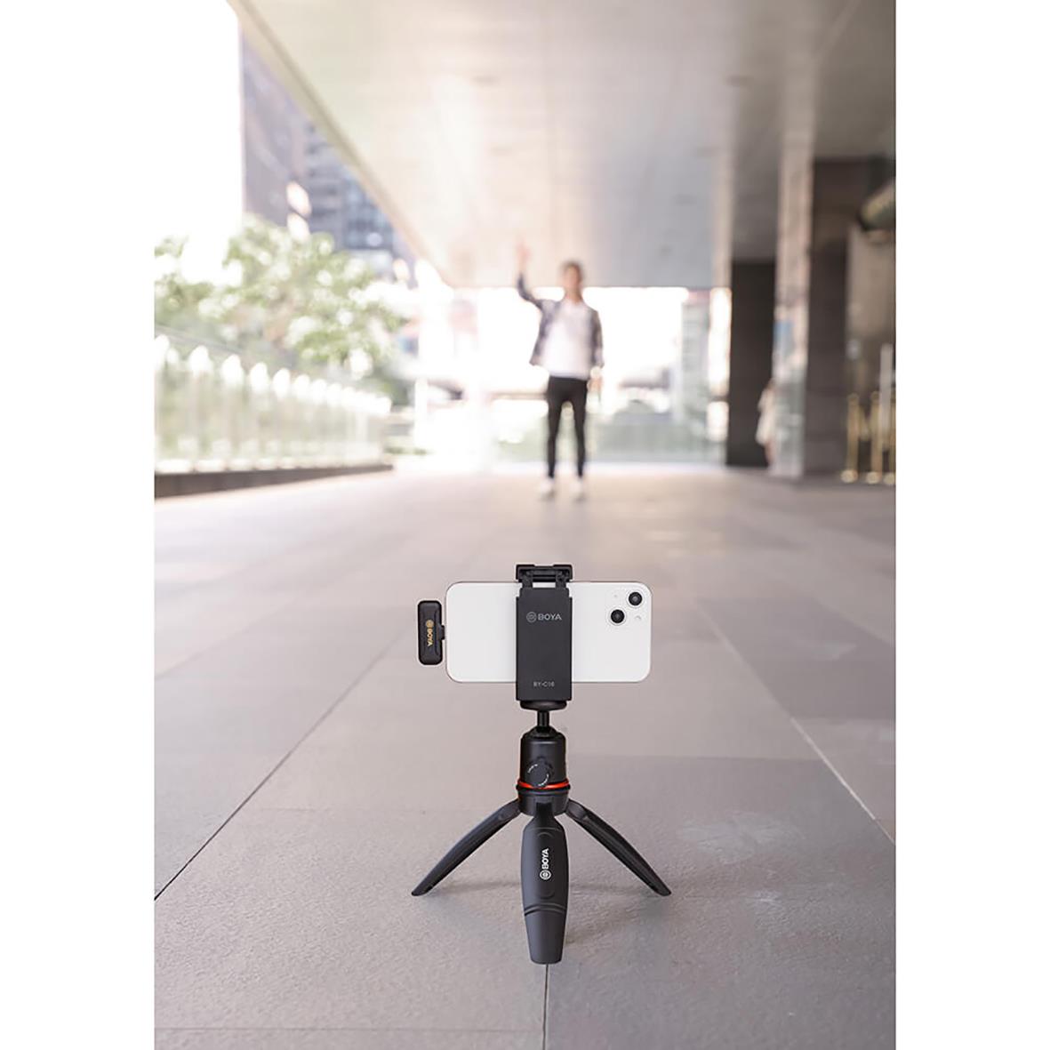 Trådlöst mikrofon BY-WM3 för Lightning kopplat till smartphone på ett stativ med person i bakgrunden