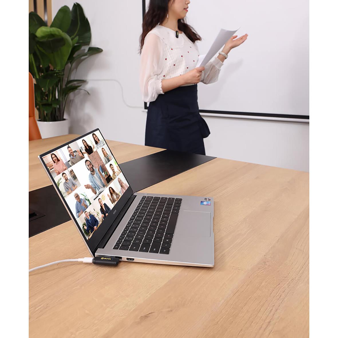 Kvinna håller presentation framför whiteboard, laptop på bordet med videomöte