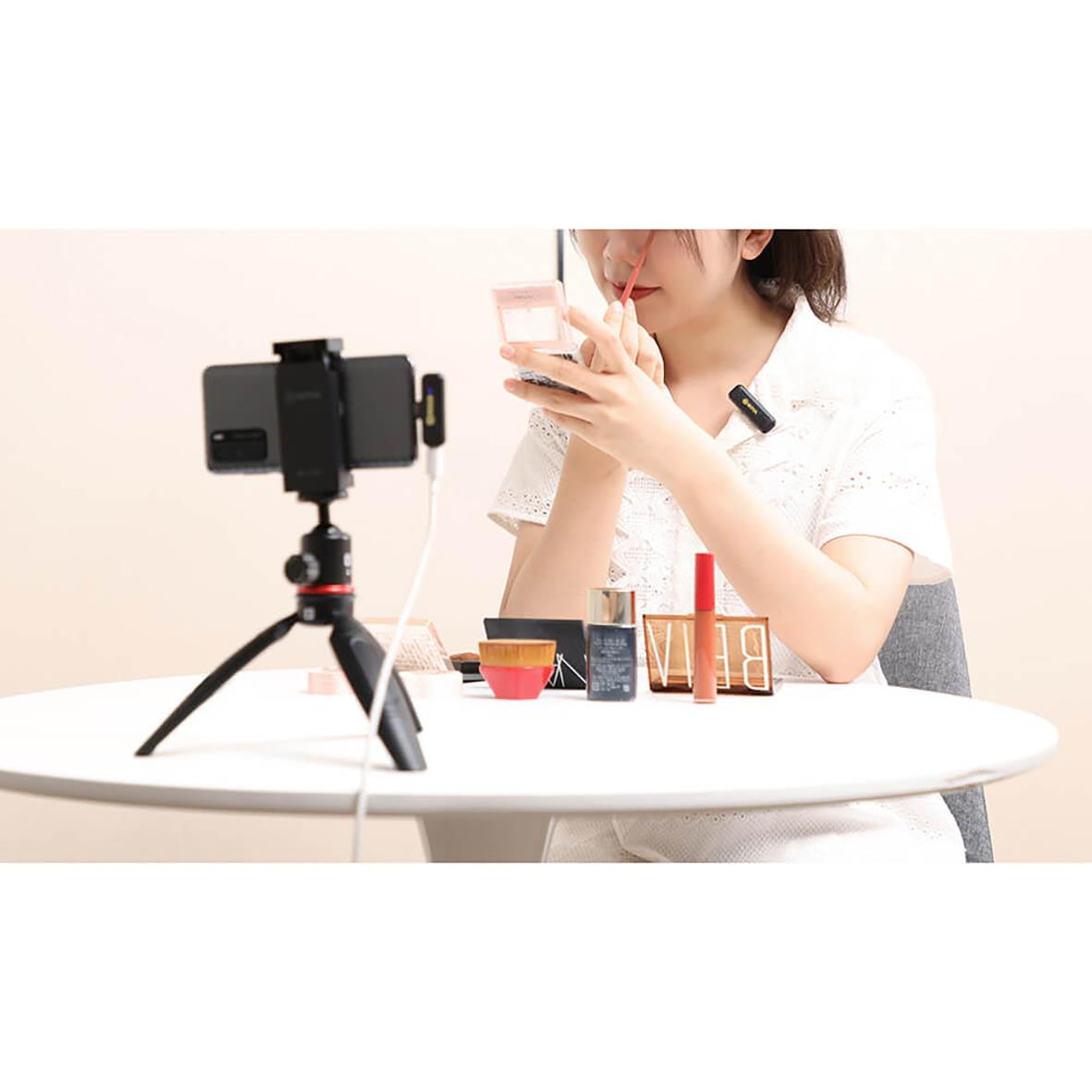 Kvinna använder trådlöst mikrofon för videoinspelning eller streaming vid bord