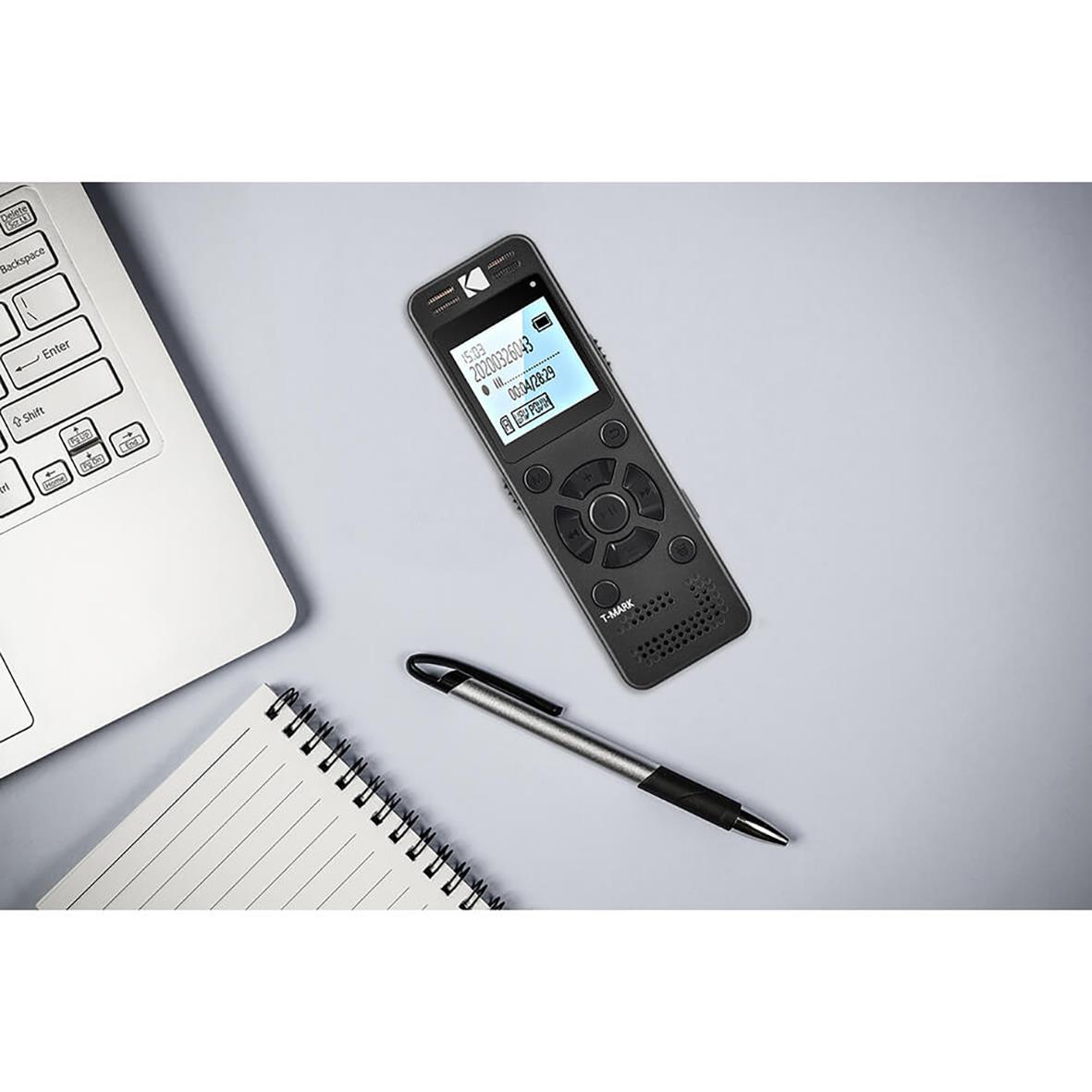 Diktafon Kodak VRC350 placerad på ett skrivbord bredvid en laptop, anteckningsblock och penna