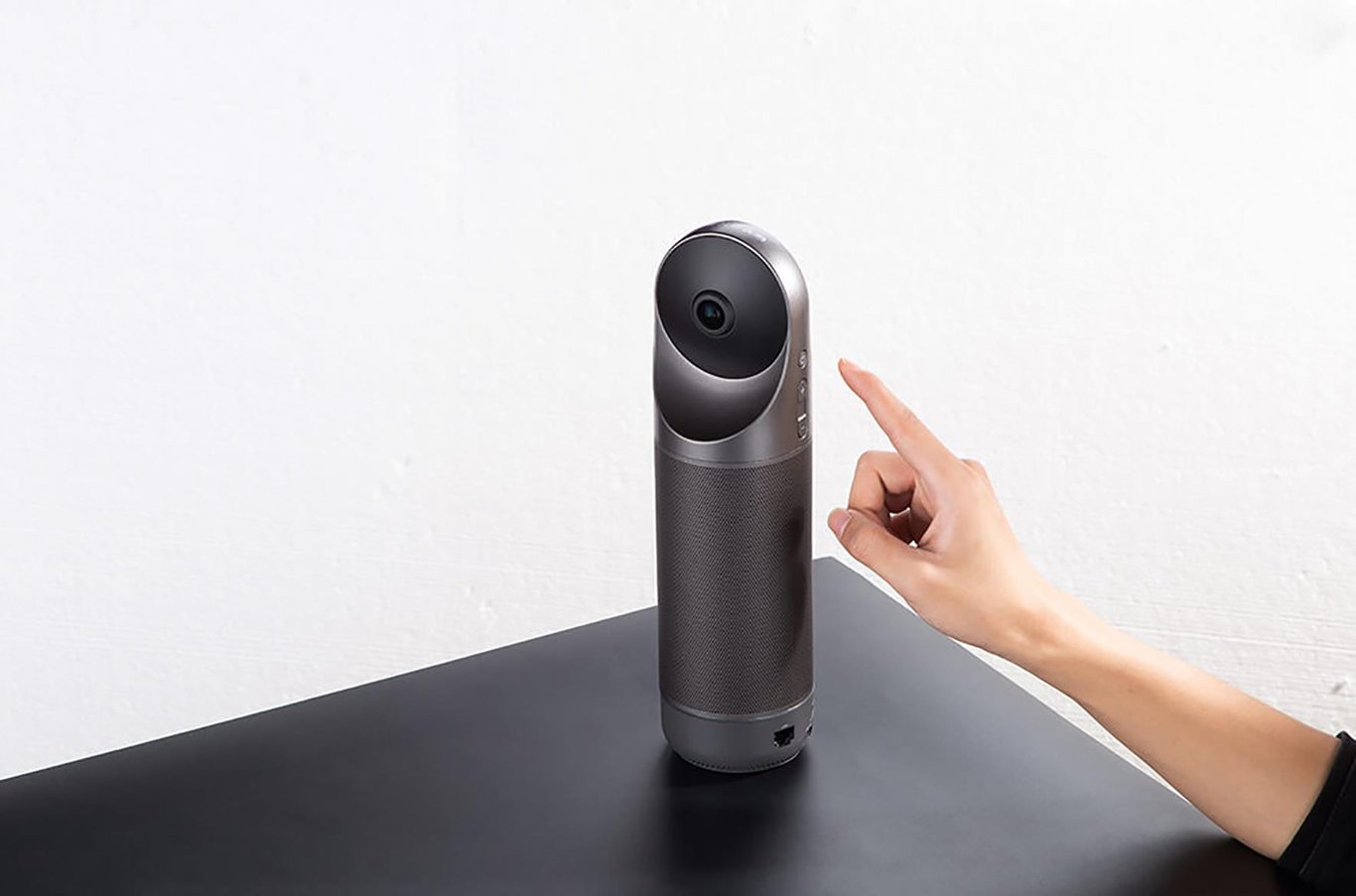 Konferenskamera Kandao Meeting Pro på bord med hand som pekar mot den