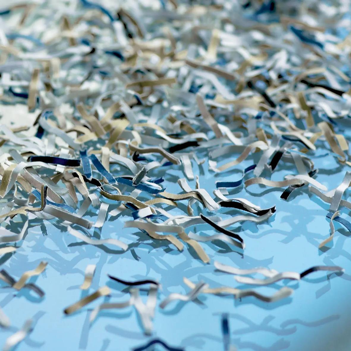 Krossade papperstrimlor från dokumentförstörare Dahle Team 506 P5 på en blå yta